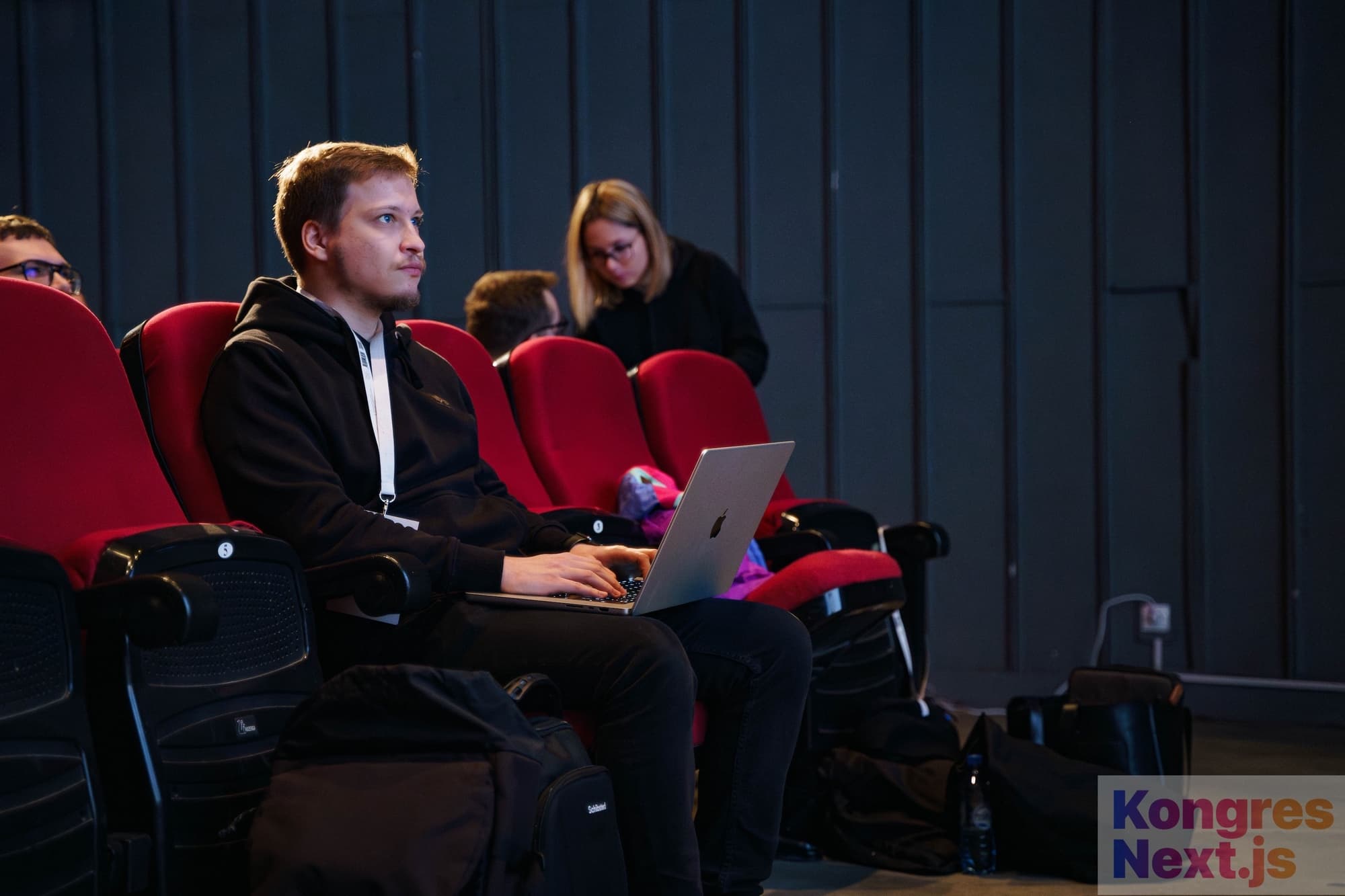 The speaker is preparing for a lecture with laptop on his lap